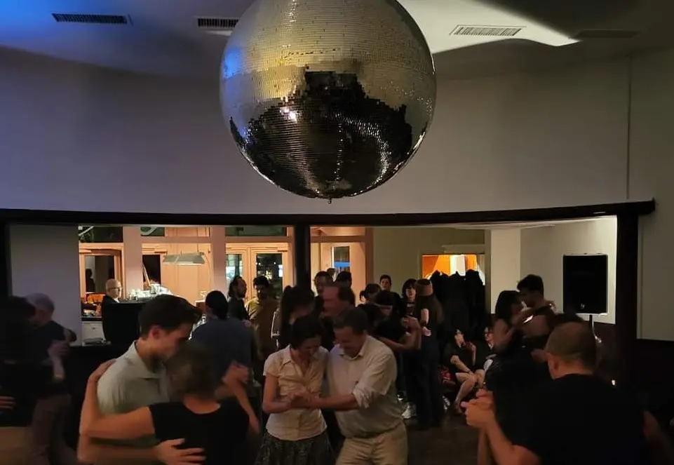 Milonga Pizza Tango Charly à Fribourg – ambiance conviviale et danse de tango argentin. Danseurs de tango lors de la milonga Pizza Tango Charly à Fribourg sous une boule à facettes.
